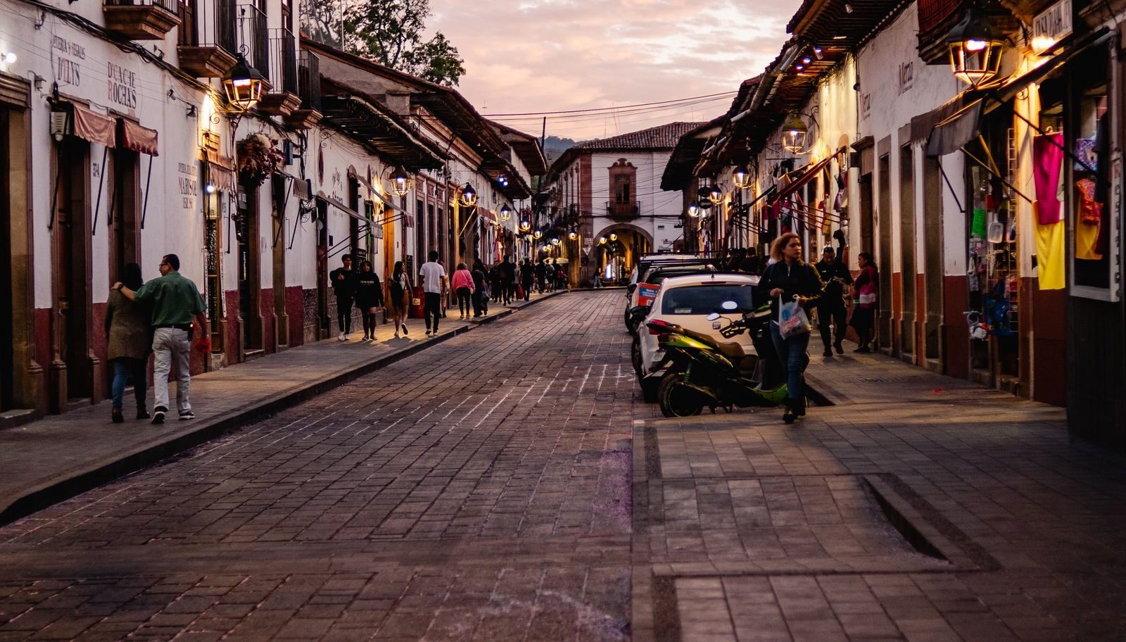 Shopfronts lining a main street at sunset; signage small and generic.