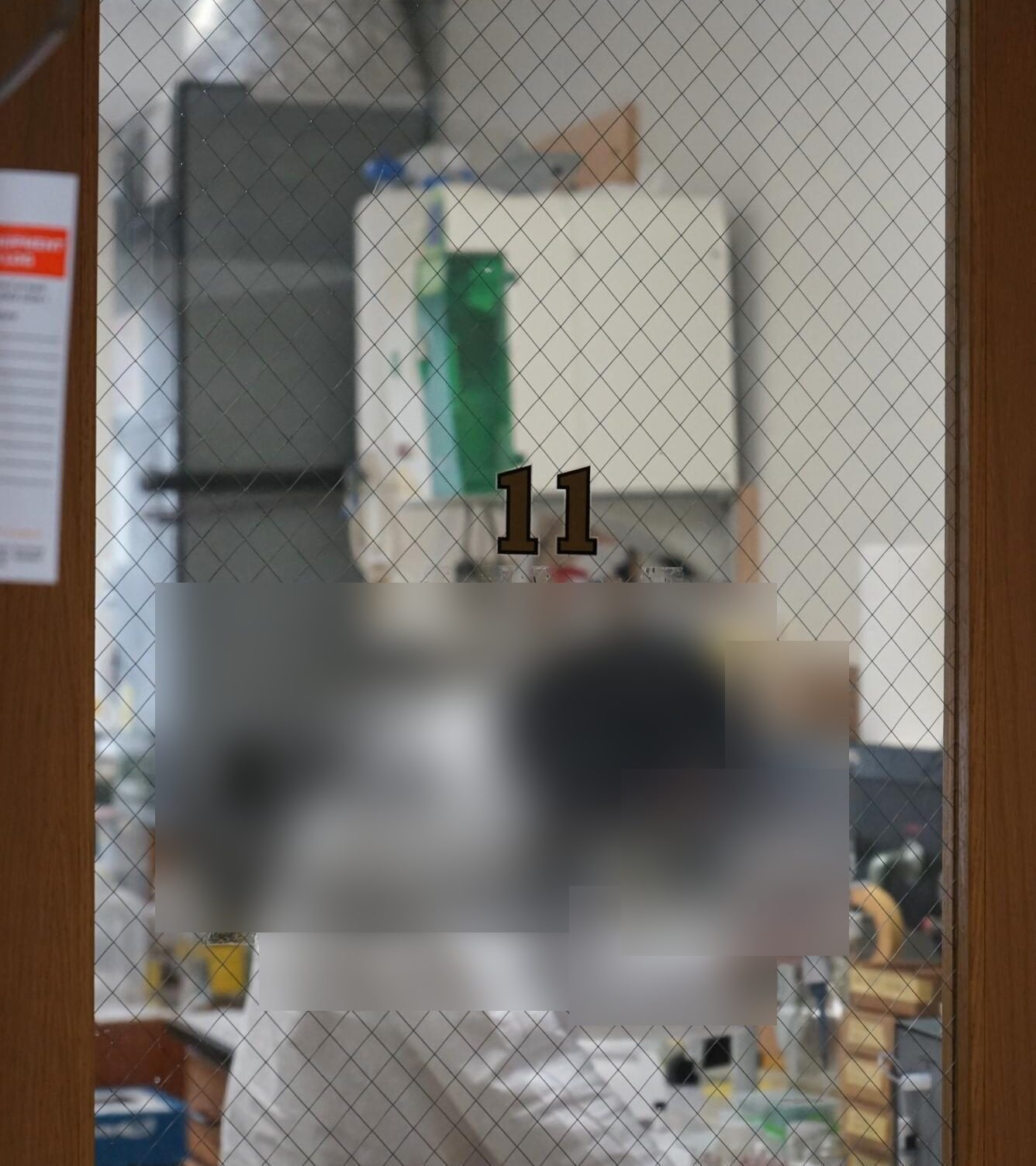 A controlled research laboratory seen through a glass wall, the work inside out of focus.